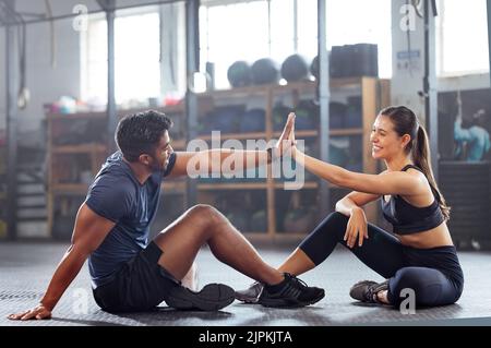 Gym wellness couple high five for success or good exercise and well done gesture for reaching fitness goal. Active trainer and client woman Stock Photo