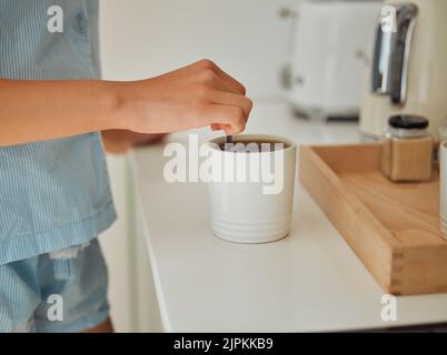 Making fresh, hot morning coffee indoors on a kitchen counter to start the day. Hand closeup of preparing a warm beverage and drink inside with a Stock Photo
