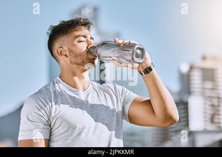 Fitness, healthy thirsty man drinking water while he is exercising outside in sportswear. Runner, cardio workout and active lifestyle for strong Stock Photo