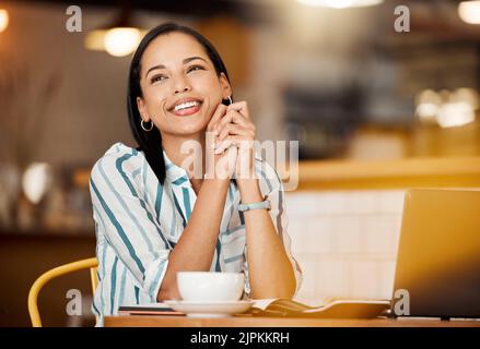 Thinking, smiling and happy young woman remote online employee day dreaming in a coffee shop. Modern female startup entrepreneur with a satsifed smile Stock Photo