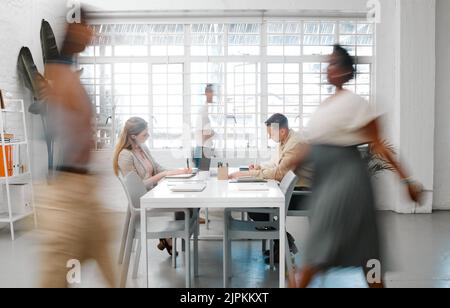 Blurred designers, marketing or freelance professionals working together in a modern office. Business men and women busy, walking and active in a Stock Photo