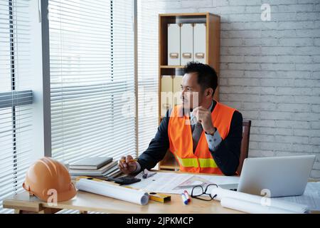 Portrait of pensive Filipino engineer working in his office Stock Photo