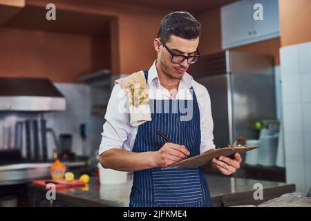Time for the inventory checklist. a man working at a restaurant. Stock Photo