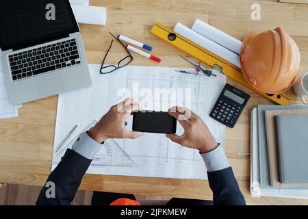 Hands of businessman taking photo of construction plan Stock Photo