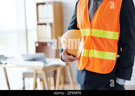 Cropped image of engineer with hardhat standing in office Stock Photo