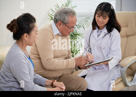 Smiling doctor showing medical test results to senior patients Stock Photo