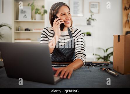 Female fashion entrepreneur on a phone call taking online packaging order for new tailor design or dress. Happy small business owner seamstress with Stock Photo