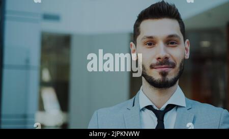 Portrait of successful young smiling businessman looking into camera in modern office indoors Stock Photo
