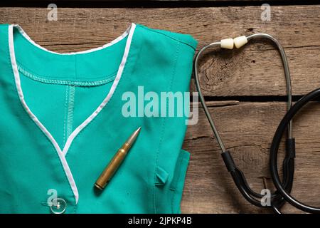 A medical uniform on which a bullet flies and a stethoscope on the table, military medicine, a doctor in the war 2022 Stock Photo