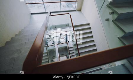Top view of two businessmen meet at stairs in modern office center and talking while having break time Stock Photo