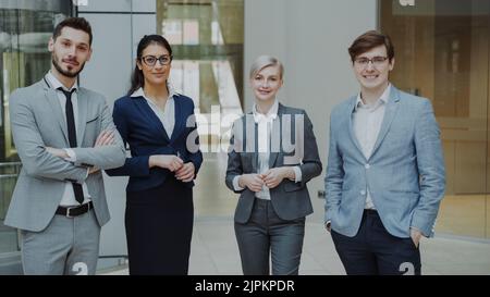 Portrait of group of business people smiling in modern office indoors. Team of businessmen and businesswomen standing together Stock Photo