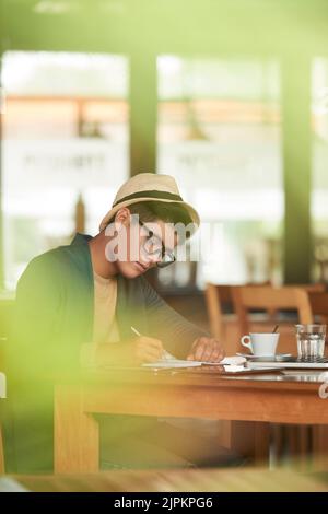 Handsome Asian young man drinking coffee and writing in notepad Stock Photo