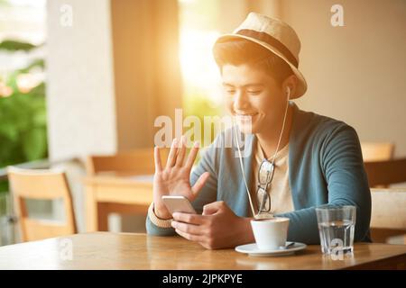 Cheerful Vietnamese man using smartphone to videocall to his friend Stock Photo