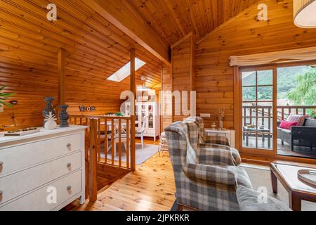 Beautiful interior of a living room with view of terrace and dining area in a wooden house Stock Photo