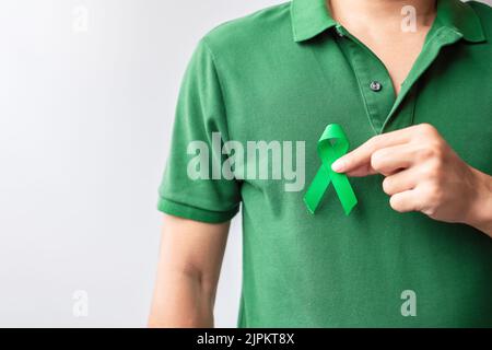 Hand holding green Ribbon for Liver, Gallbladders, bile duct, cervical, kidney Cancer and Lymphoma Awareness month. Healthcare and world cancer day co Stock Photo