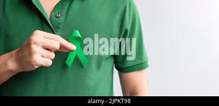 Hand holding green Ribbon for Liver, Gallbladders, bile duct, cervical, kidney Cancer and Lymphoma Awareness month. Healthcare and world cancer day co Stock Photo