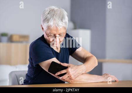 Woman Testing Glucose Level With Continuous Glucose Monitor On Mobile Phone Stock Photo