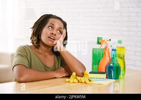 Tired bored housewife at table with detergents Stock Photo