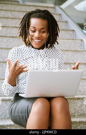 Excited pretty business woman with laptop videocalling to coworker Stock Photo