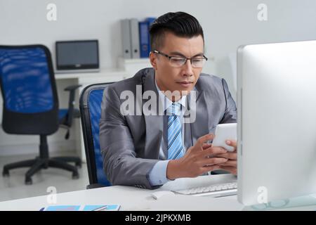 Asian entrepreneur using application on his smartphone Stock Photo