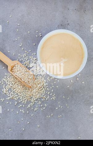 Pure sesame tahini with sesame seeds on mottled grey with copy space Stock Photo