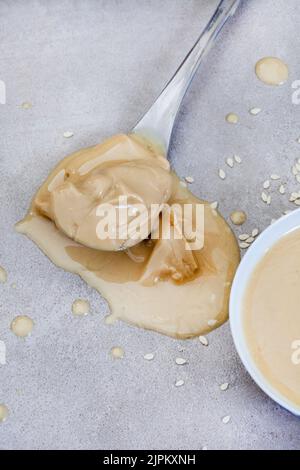 Pure sesame tahini with sesame seeds on mottled grey with copy space Stock Photo