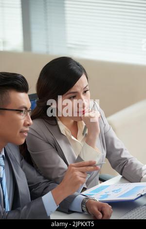 Financial analysts discussing business report at meeting Stock Photo