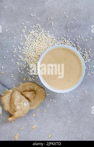 Pure sesame tahini with sesame seeds on mottled grey with copy space Stock Photo