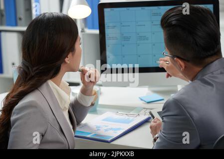 Business people discussing calender of upcoming month Stock Photo