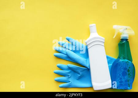 Rubber gloves and detergents on brigh yellow background Stock Photo