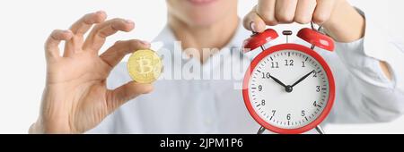 Woman is holding golden bitcoin and alarm clock Stock Photo