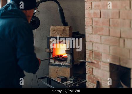 Blacksmith forge oven with hot flame. Smith heating iron piece of steel in fire of red hot forge Stock Photo