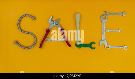 Word SALE from letters made up of plumber's tools on the yellow background.. Stock Photo