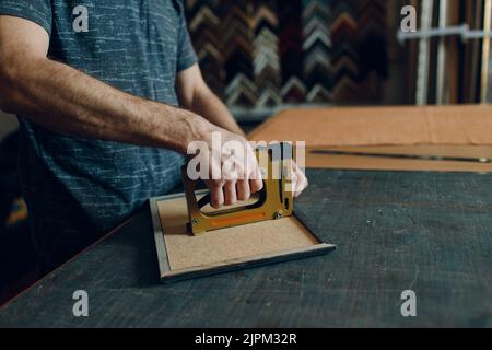 Framing Workshop. Making assembly stapler brackets baguette handmade picture frame at studio. Stock Photo
