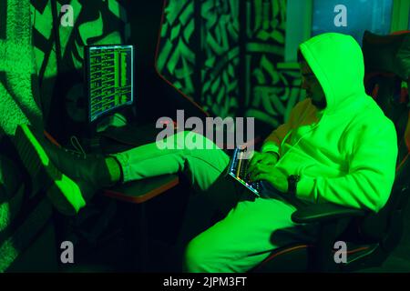 Hacker in hoodie working hacks code site on personal computer Stock Photo
