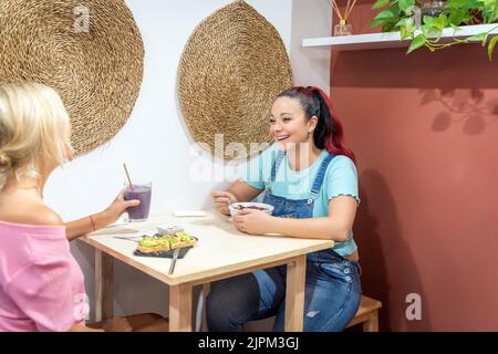 Friends enjoying time together while having a healthy breakfast in a cafe. Friendship and food concept. Stock Photo