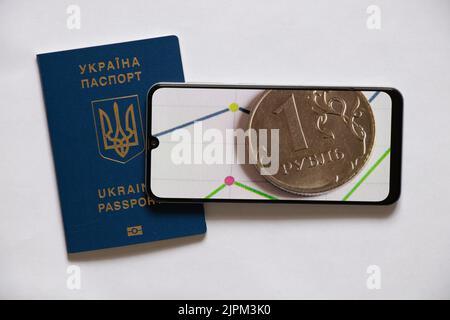 The Russian ruble and a histogram with statistics on the phone on a white background and a foreign passport lies nearby. Financial sanctions against R Stock Photo