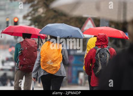 Munich, Germany. 19th Aug, 2022. Passers-by protected themselves with their umbrellas in the rain. Further rainfall is also forecast for some regions in Bavaria. Credit: Peter Kneffel/dpa/Alamy Live News Stock Photo