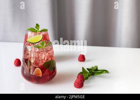 Fresh summer lemonade with raspberry, lime, soda water, and ice in glasses. Stock Photo