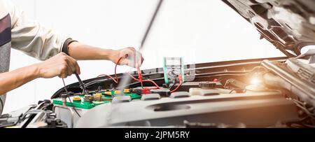Mechanic checking the car's electrics with a multimeter. Stock Photo