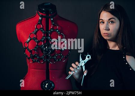 Tanner woman portrait with leather harness on mannequin. Stock Photo