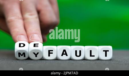 Hand turns dice and changes the expression "my fault" to "default". Stock Photo
