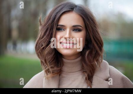 Portrait of happy young brunette woman with wavy brown medium hairstyle, waves with side volume Stock Photo