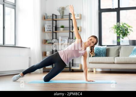 happy woman doing plank exercise on mat at home Stock Photo