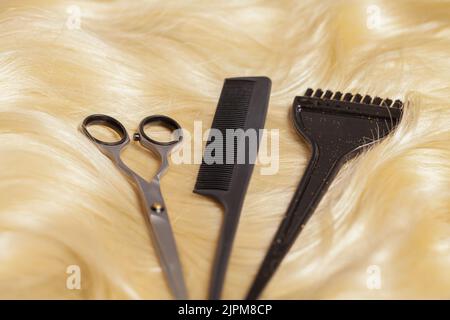 Professional scissors, comb and hairdressing brush on blonde hair Stock Photo