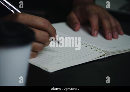 Man hand holding pen write note diary on book. Stock Photo