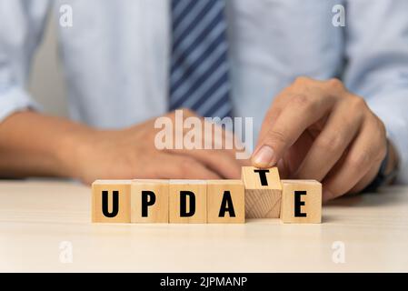 Businessman hand holding wood cube block text update on desk concept. Stock Photo