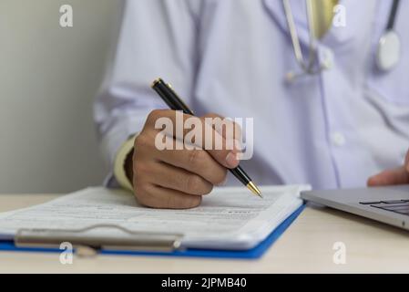 Doctor hand holding pen write and paperwork document patient treatment on clipboard.Business health care concept. Stock Photo