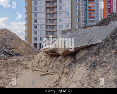 Closeup of a pile of sand and a huge concrete block in foreground and new high-rise buildings in the background of a building site in Kyiv, Ukraine. Stock Photo