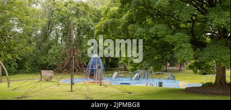childrens play equipment in a local park, green trees and grass, no people Stock Photo